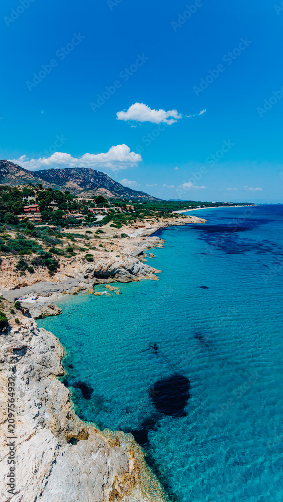 Obraz premium Drone aerial view of a rocky Mediterranean coastline with crystal clear turquoise sea, mountains, and secluded bays under a blue sky. Luxury travel, resort destination, summer vacation, coastal touris