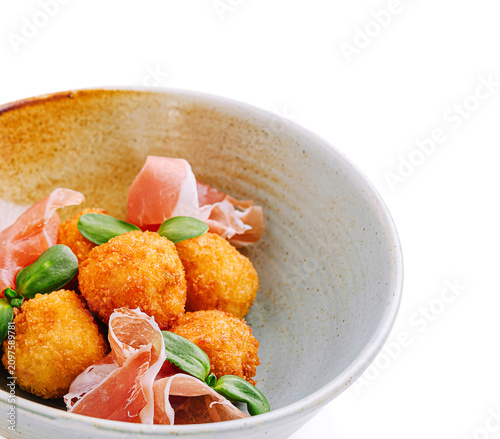 Fotografie Savory golden croquettes sit nestled in a rustic bowl, garnished with fresh greens and strips of ham