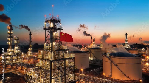 Industrial petrochemical plant at twilight with smoke stacks and storage tanks