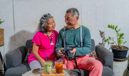 Photography Elderly couple enjoys drinks while looking at pictures in a cozy indoor setting