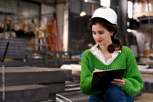 Fényképezés Female Inspector Writing Notes Near Steel Beams