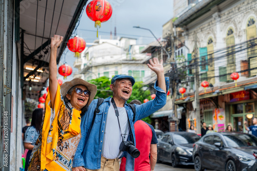 Elderly couple enjoying a festive moment in a busy street during a celebration with lanterns in the background