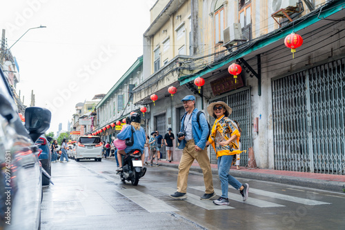 Fotografía Couple walks across street with festive lanterns in the background during a clou