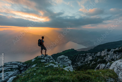 Adventure hiker stands on a mountain summit at sunset for exploration and travel, at Monte Baldo Natural Park, Altissimo Refuge 