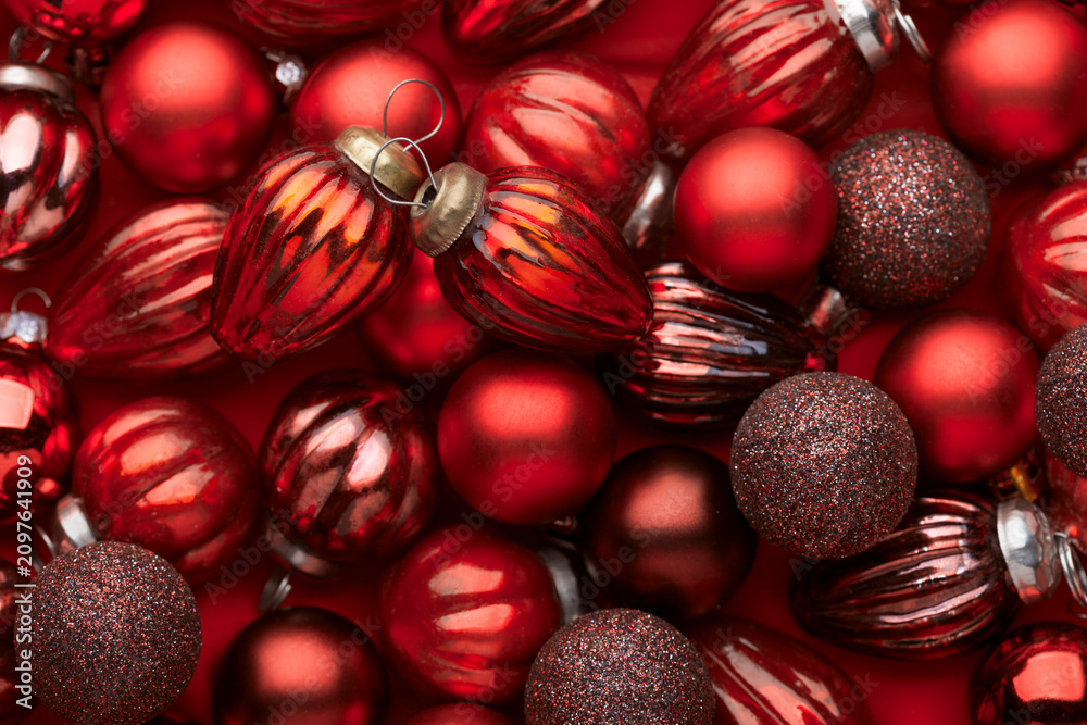 Fototapeta premium Close up of pile red Christmas ornaments, various size, shades and textures. Christmas Holiday background. Flat lay