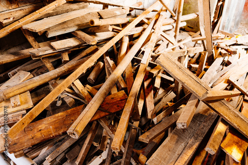 Messy pile of scrap wood, lumber planks, and bamboo poles on a construction site