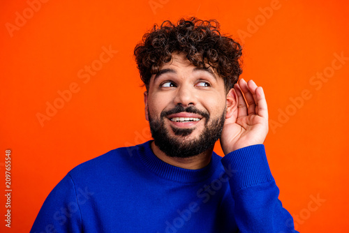 Konstfotografi Young man listening intently with hand to ear in bright portrait, curious expres