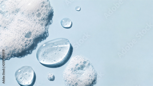 transparent cosmetic gel drop with soap bubble foam on blue background. Skincare product texture sample for beauty industry. Moisturizing serum closeup for dermatology and health concept