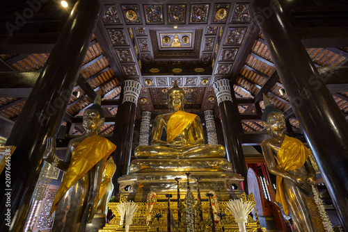Εκτύπωση καμβά Golden Buddha statue in ornate temple hall with carved ceiling and wooden column