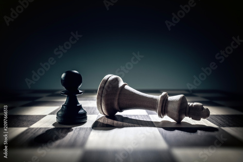 Photos Pawn chess piece standing over defeated king concept for success, winning, confi