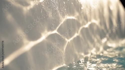 Water flows over a white surface and creates reflections in bright light