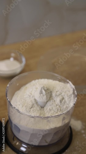 Woman pouring flour over butter in a blender to prepare dough for baking a pie or cookies