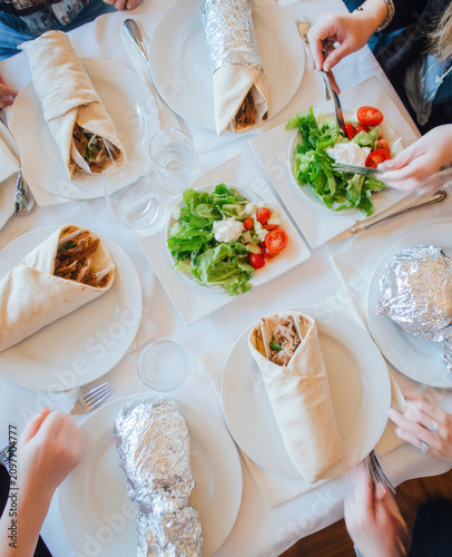 People enjoying delicious wraps and fresh salads at a table gathering.