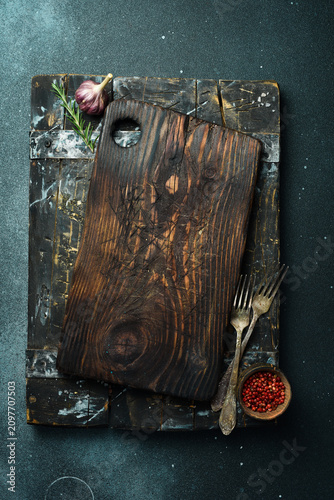 Wooden kitchen tray. Kitchen textured cutting board. Kitchen decorative accessories. On a dark background. Top view. Free space for text.
