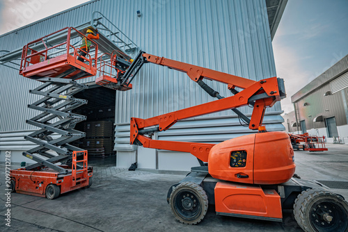 Workers are working on the Orange articulate boom lift or telescopic boom lifts and bucket crane mounted on truck for working at heights and articulating boom