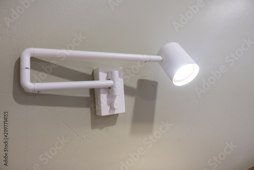 Bild auf Leinwand White adjustable wall lamp casting warm light and shadow on painted plaster wall