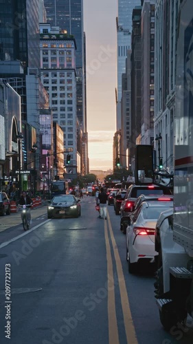 Manhattan street canyon in New York City with bustling traffic, iconic yellow taxi, glowing billboards during warm sunset creating an urban atmosphere. 02,02,2026, New York, USA, 