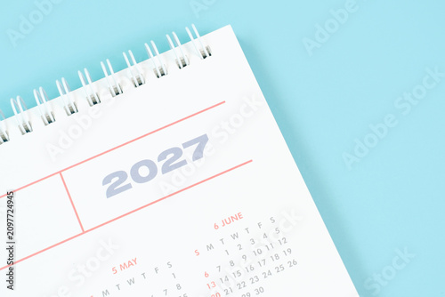 Paper calendar for 2027 on blue background close-up top view.