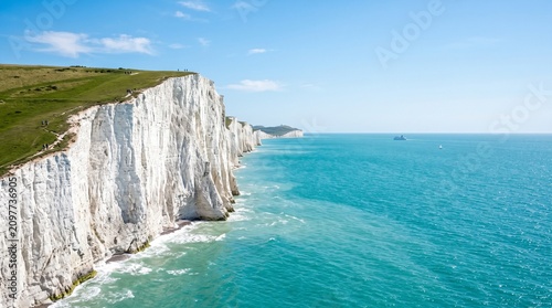 Stunning landscape view of the iconic white chalk cliffs of Beachy Head in East Sussex, England, towering over the bright turquoise waters of the English Channel under a clear blue summer sky