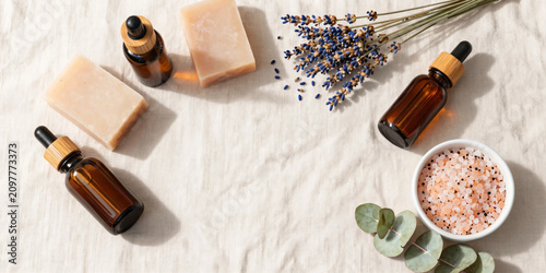 Premium Flat Lay of Natural Herbal Skincare Products with Botanical Soaps, Amber Serum Bottles, Bath Salts, and Fresh Greenery on Soft Pastel Background for Clean Beauty and Wellness Branding