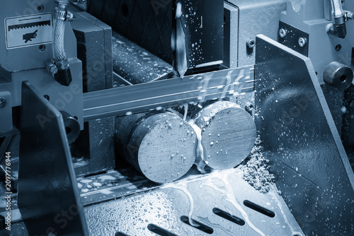 Industrial bandsaw machine performing a material preparation process cutting a metal rod.
