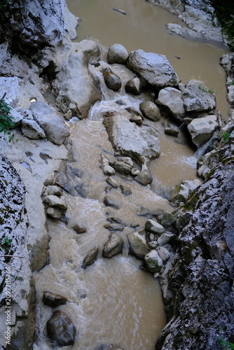 Aerial view of muddy stream flowing through rocky creek bed