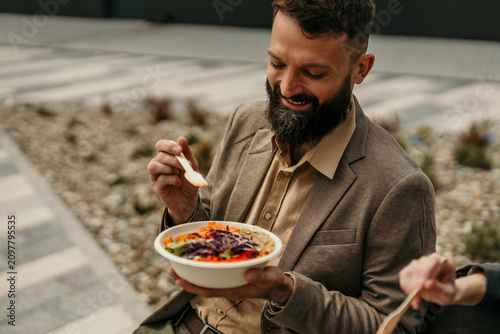 Man enjoying healthy salad bowl during outdoor business lunch