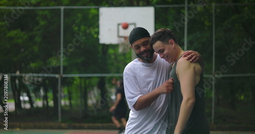 Foto Young multiethnic men greeting each other with handshake on outdoor basketball c