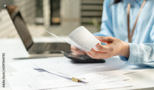 Obraz na plátně Businesswoman hands review receipts beside laptop and calculator