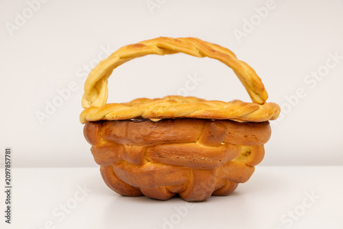 Braided bread basket with golden crust and handle on white background