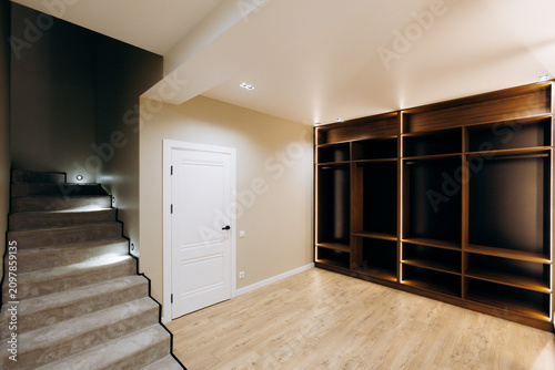 Fotografie Finished basement entry with carpeted staircase, white landing door, and illumin