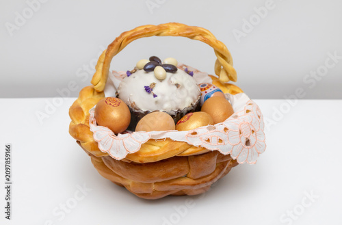 Easter basket with braided bread, decorated eggs, and sweet bread topped with icing and edible flowers