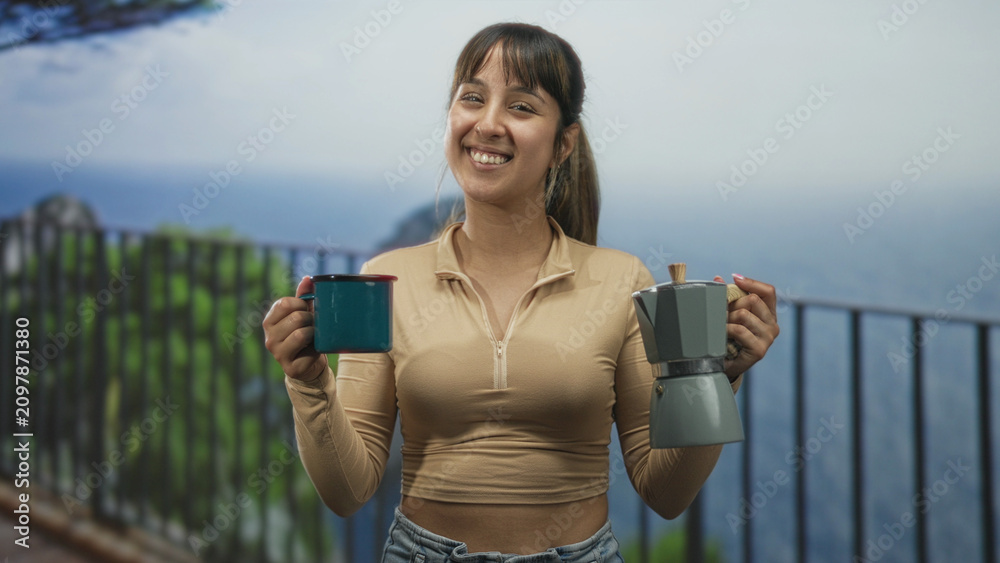 Obraz premium Woman holding teal mug and moka pot, smiling while offering cups on a balcony overlooking ocean and cliff; serenity morning ritual.