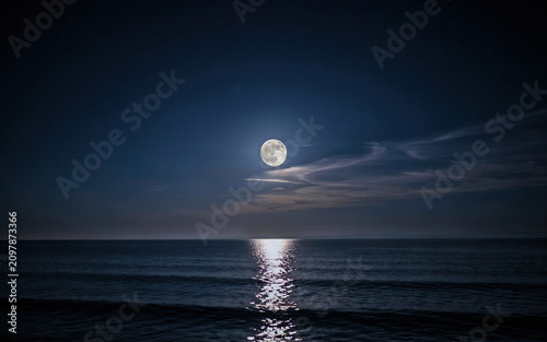 Stunning full moon shining brightly over a calm ocean with moonlight reflection on water transparent background