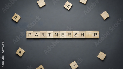 Wooden letter blocks spelling the word partnership on a dark background