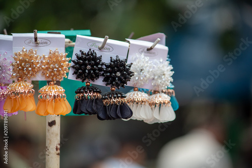 Картината върху платно Colorful fashion earrings displayed on a retail market stand with selective focus and blurred background, showcasing affordable costume jewelry for shoppers