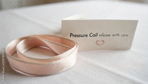 Soft pink ribbon resting on a table with a card that reads 