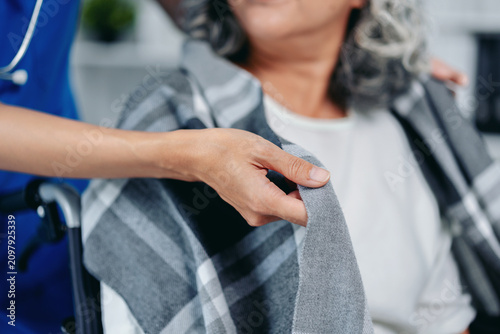 Medical professional provides warm blanket comfort senior patien