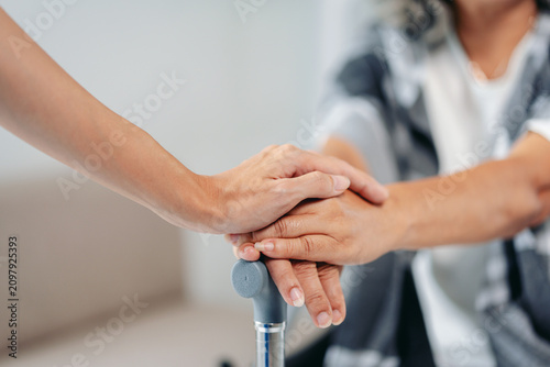 Caregiver offers compassionate support senior hand on walking ca