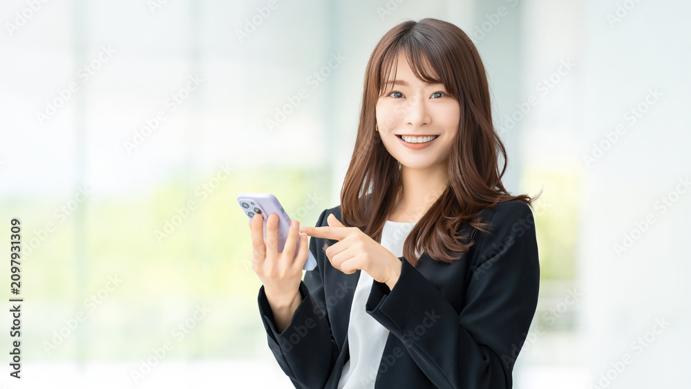 Fototapeta premium スマートフォンを使う笑顔の女性・ビジネスウーマン