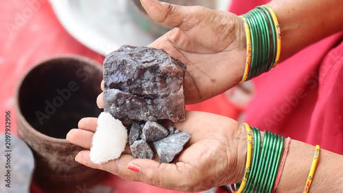 Tableau sur toile Close-up of an Indian woman's hands wearing traditional green bangles holding large raw chunks of natural black salt and rock salt outdoors