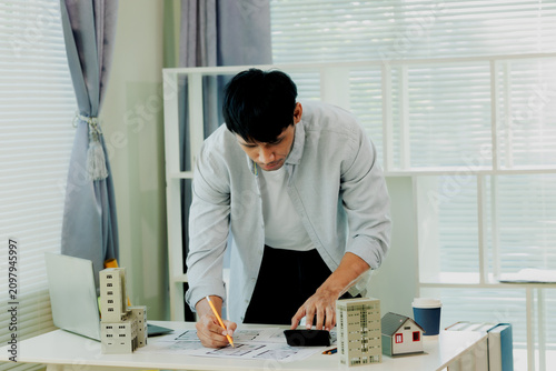 Focus on a professional Thai engineer calculating structural integrity and construction costs for a high-rise project