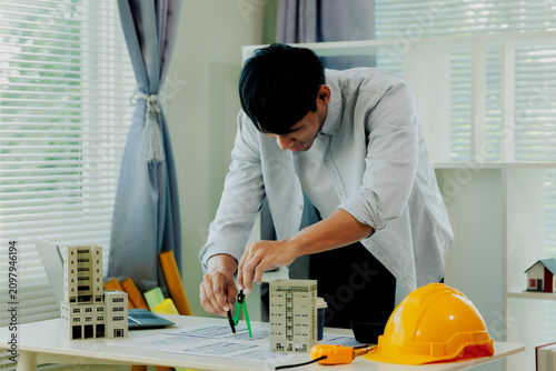 Fotografie Determined site engineer using calculator and blueprint layouts to ensure accurate building integrity data