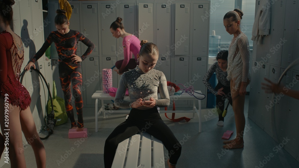 Obraz premium Teenage Rhythmic Gymnast Dealing With Severe Stage Fright and Psychological Pressure Before Tournament. Girl Turns on Playlist on Smartphone, Inserts Earphones, Shuts Eyes Tightly to Battle Anxiety.