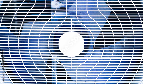 Close up view of an air conditioner fan behind a protective metal grille