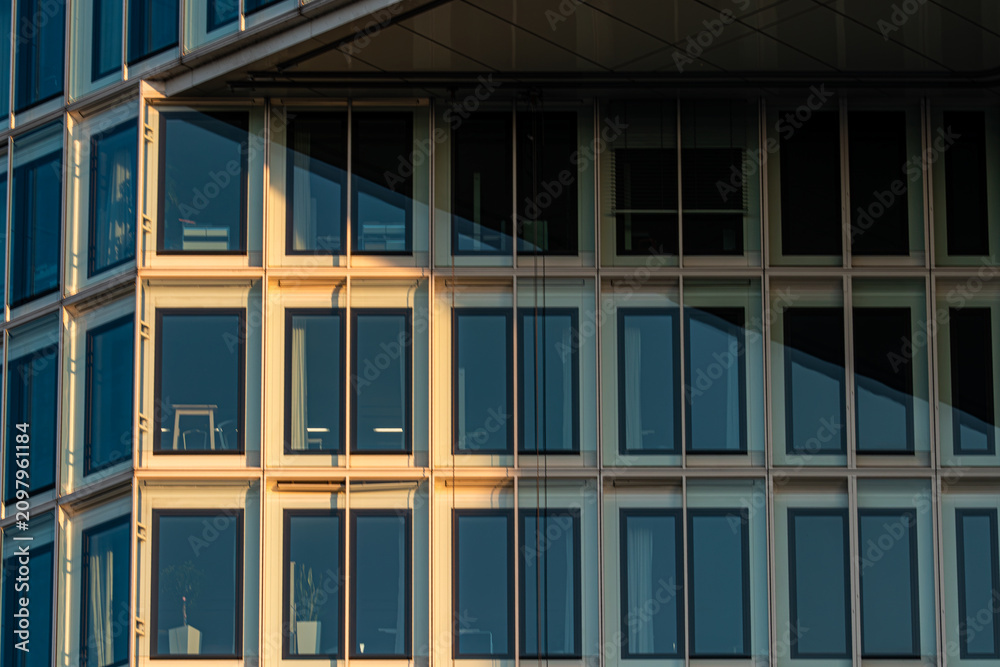 Obraz premium Modern Office Building Glass Facade with Diagonal Shadow and Sunset Light
