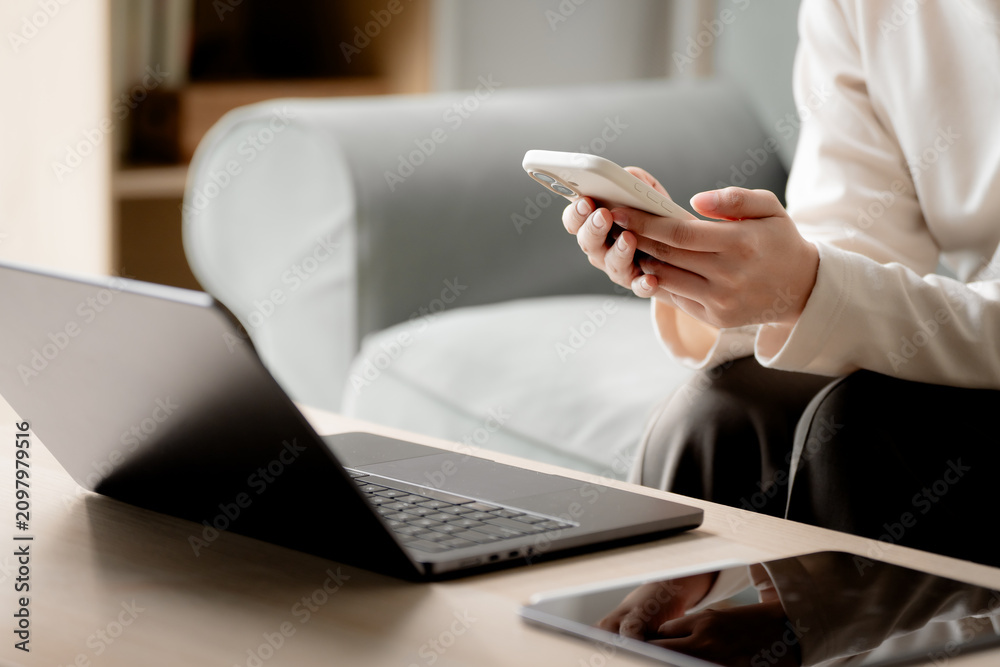 Fototapeta premium Remote work lifestyle. Anonymous woman using laptop while working from home in a modern living room with copy space. Remote work, laptop, home office, productivity, freelance