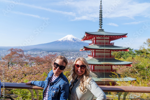 Two women travelers pose at Chureito pagoda, Mt Fuji mountain viewpoint in Shimoyoshida, Japan. Enjoying view