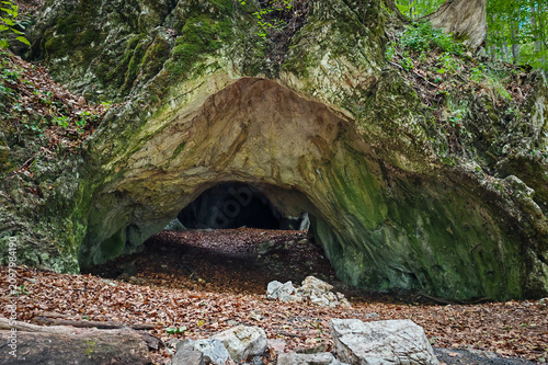 Foto Wide view of the natural entrance of Kőrös-lyuk Cave in the Bükk Mountains, northeastern Hungary, surrounded by limestone cliffs and lush beech forest