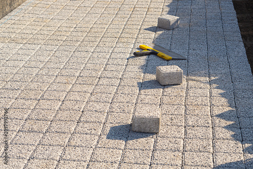 Foto Pavement area with freshly laid paving stone tiles POV view with a few new remaining blocks and a large spatula
